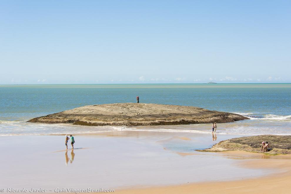 Imagem de turistas na beira do mar na Praia do Morro.